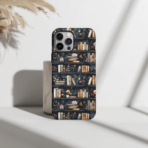 Pu&ograve; includere: Una custodia per telefono nera con un motivo di librerie piene di libri e fiori. La custodia ha un ritaglio per la fotocamera e uno sfondo nero.