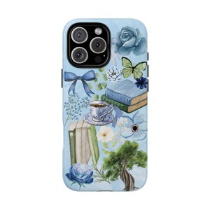 May include: A blue and white phone case with a floral design. The design includes a cup of tea, books, flowers, and a butterfly. The phone case is for an iPhone 13 Pro Max.