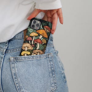 May include: A black phone case with a colorful mushroom design. The case is in a back pocket of blue jeans.