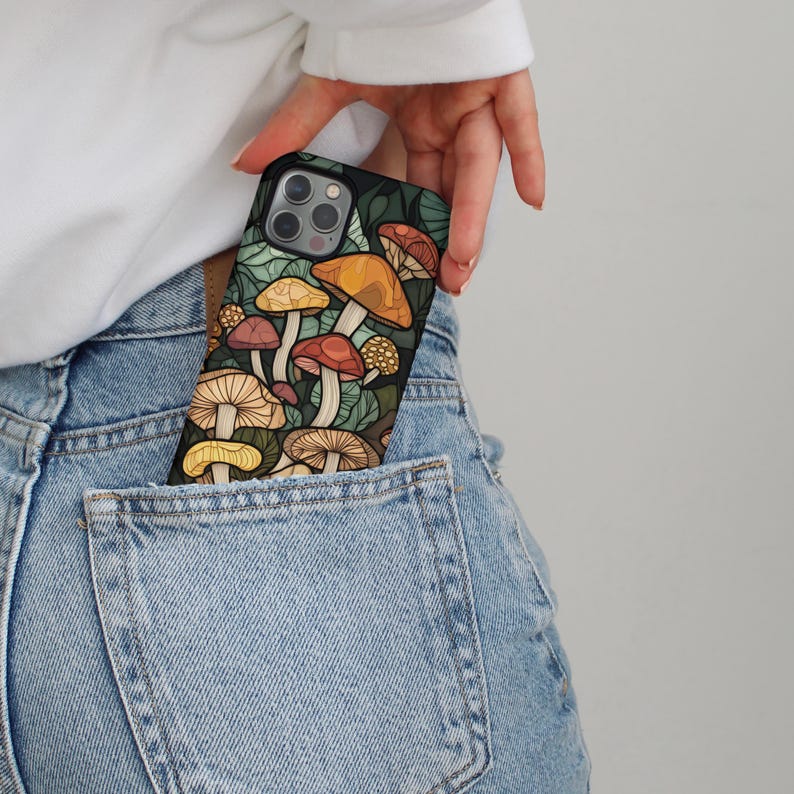 May include: A black phone case with a colorful mushroom design. The case is in a back pocket of blue jeans.
