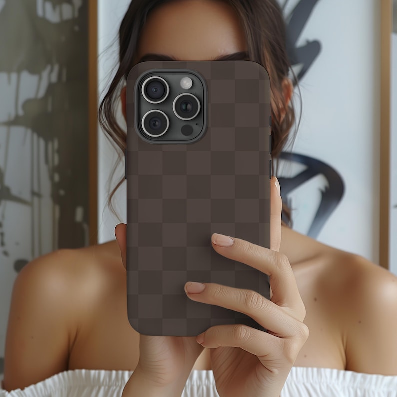 May include: A brown phone case with a checkered pattern. The case has a camera lens cutout with three lenses.