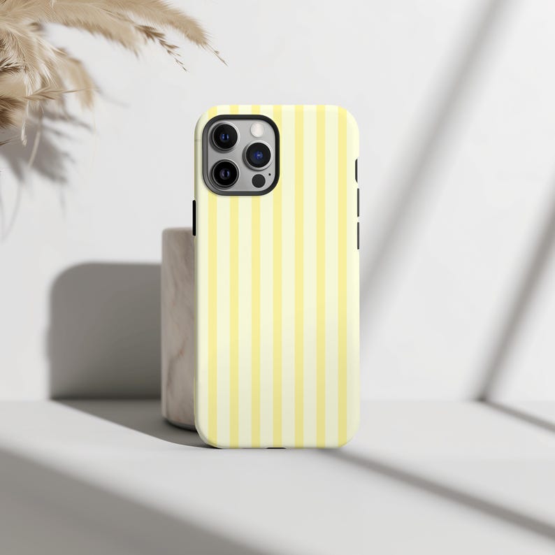 Pode incluir: Uma capa de telefone listrada amarela e branca para um iPhone.