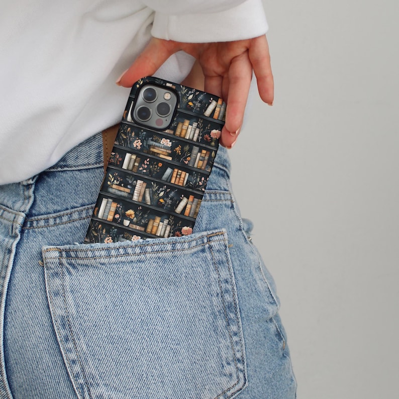 Pu&ograve; includere: Una custodia per telefono nera con un design a libreria con libri e fiori. La custodia &egrave; in una tasca posteriore di jeans blu.