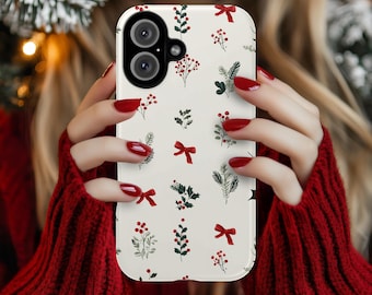Puede incluir: Una funda de teléfono blanca con un estampado festivo de lazos rojos, bayas y ramitas verdes. La funda tiene un recorte para una cámara de doble lente. El diseño evoca un tema navideño o invernal.