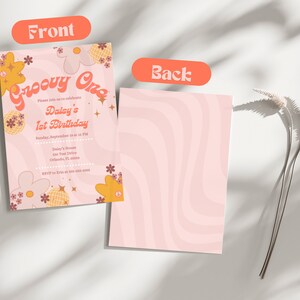 Op de afbeelding: Een dubbelzijdige uitnodiging met een groovy thema. De voorkant heeft de tekst "Groovy One" en details voor een eerste verjaardag. De achterkant heeft een roze golfpatroon. Bloemen- en discobal-afbeeldingen versieren de uitnodiging.