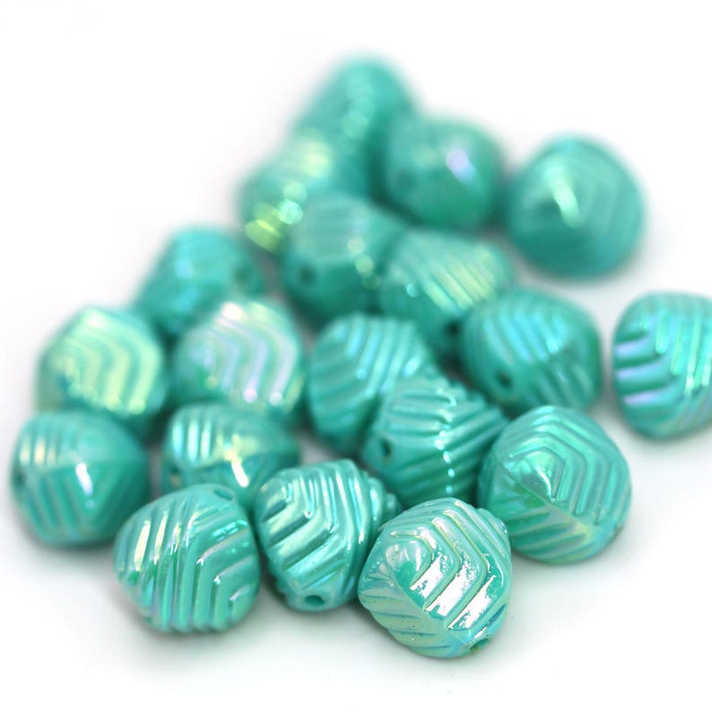 May include: A collection of iridescent turquoise beads with a geometric pattern. The beads are clustered together, showcasing their multifaceted design and glossy finish. These beads are ideal for jewelry making and crafting projects.