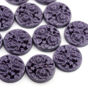 May include: A set of 10 purple resin cabochons with a raised floral design. Each cabochon features a cluster of roses and leaves.