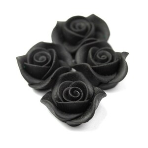 May include: Four black fabric roses, each with a curled center, are arranged in a cluster on a white background.