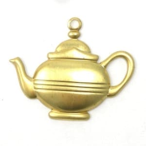 Puede incluir: Un amuleto de metal dorado en forma de tetera con un cuerpo redondeado y un pequeño pico. El amuleto tiene un lazo en la parte superior para colgarlo.