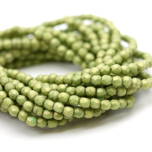 May include: A strand of light green faceted glass beads. The beads are small and have a matte finish.