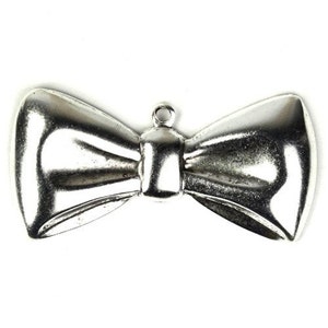 May include: A silver metal bow tie charm with a loop at the top for attaching to a necklace or bracelet.