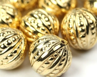 Könnte beinhalten: Nahaufnahme von goldfarbenen runden Perlen mit einer strukturierten Oberfläche. Die Perlen haben ein erhabenes, gemustertes Design.