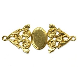 May include: A gold-colored metal filigree connector with an oval center and floral accents. The connector has two loops on either end and is designed for jewelry making or crafting projects.