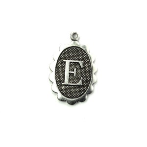 May include: Silver charm with a scalloped oval frame and a textured background. The letter "E" is centered in the frame.
