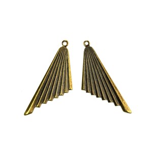 Puede incluir: Dos colgantes de metal de color dorado en forma de abanico con un bucle en la parte superior para sujetar a las joyas.