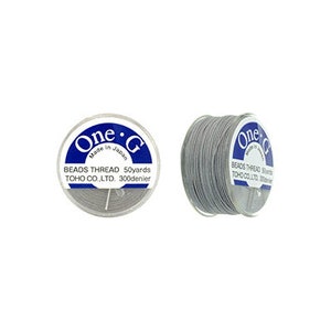 May include: A spool of gray beading thread, labeled "One-G Beads Thread 50yards TOHO CO.,LTD. 300denier" and "Made in Japan".