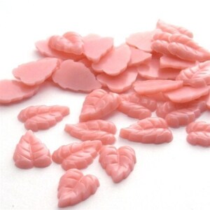 May include: A large quantity of pink plastic leaf-shaped embellishments. These are great for adding a touch of whimsy to crafts and projects.