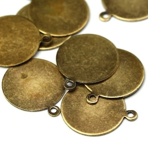 May include: A group of round, antique gold-toned metal charms with a loop on the top. The charms are smooth and have a slightly textured surface.