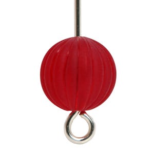 May include: A close-up of a red, ribbed sphere with a silver metal loop and a silver metal rod. The sphere is a vibrant red color and has a textured surface. The object is isolated against a white background.