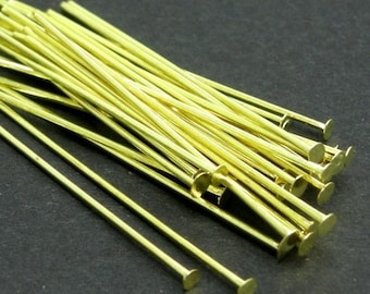 May include: A pile of gold-colored head pins with flat round heads. The pins are about 1 inch long.