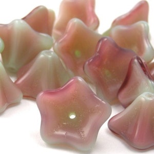 May include: A group of iridescent glass beads in shades of pink and green. The beads are shaped like stars and have a hole in the center for stringing.