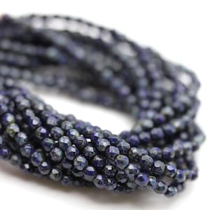 Op de afbeelding: Een streng donkerblauwe lapis lazuli kralen met een gefacetteerde afwerking. De kralen zijn klein en rond en hebben een licht metalen glans.