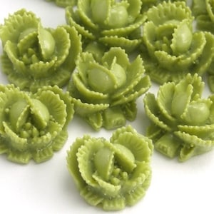 May include: A collection of 10 green, plastic, flower-shaped embellishments. The embellishments are about 1 inch in diameter and have a detailed, layered design.