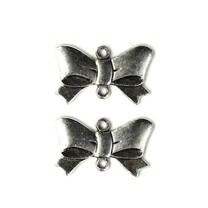 May include: Two silver metal bow charms with a loop at the top for attaching to jewellery or crafts.