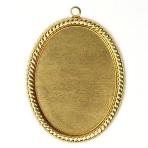 May include: A gold-colored oval pendant with a textured rope-like border. The pendant has a small loop at the top for hanging. The center is a smooth, blank oval, ready for customization. The pendant is set against a white background.