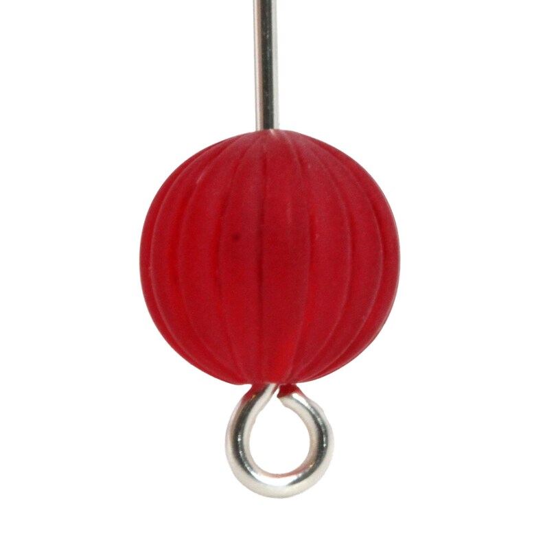 May include: A close-up of a red, spherical bead with vertical grooves. The bead is attached to a silver-colored metal eye pin and a silver-colored metal rod.