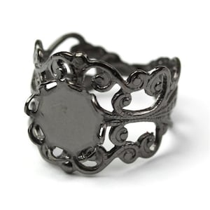May include: Black metal ring with a filigree design and a round, blank space for a cameo or other embellishment.