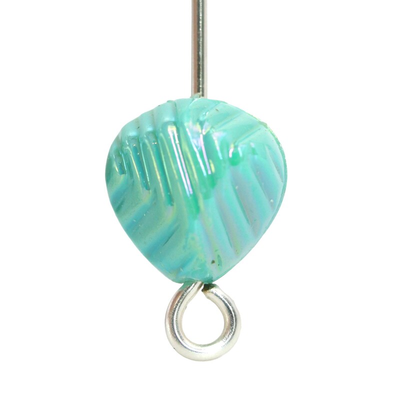 May include: A teal, leaf-shaped bead with iridescent qualities, strung on a silver-colored head pin. The bead has a textured surface with diagonal lines. The bead is approximately 0.5 inches long.