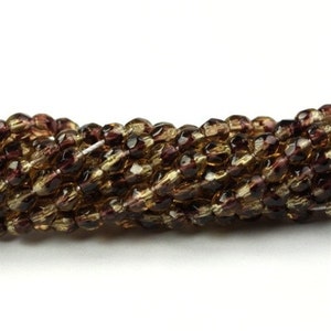 May include: A strand of brown and gold glass beads with a faceted finish. The beads are small and have a subtle shimmer.