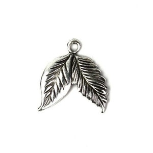 May include: Silver charm with two leaves, each with detailed veins, connected at the top with a loop for attaching to a necklace or bracelet.