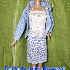 May include: A blue and white patterned doll outfit with a white top featuring silver stars and a blue jacket with white polka dots. The skirt is blue with white leaf-shaped patterns. The doll is wearing a white lace trim around the waist.  "Pattern suits daywear as well!"