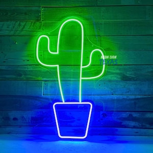 Puede incluir: Un letrero de neón verde en forma de cactus con una maceta de neón azul. El letrero dice "Neon Sign Texas".
