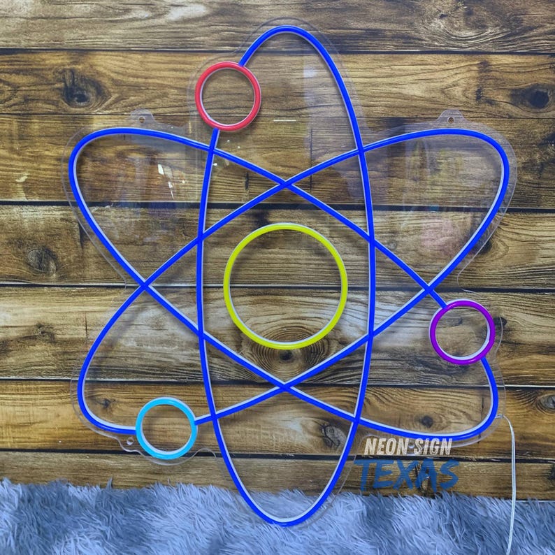 May include: A neon sign in the shape of an atom, with a blue outline and colorful circles. The sign has the text "NEON SIGN TEXAS" at the bottom. The sign is mounted on a wooden background.