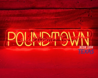 May include: Neon sign with the text "Poundtown Welcome to" in yellow letters on a red background. The sign also includes the text "Neon Sign Texas" in smaller letters below the main text.