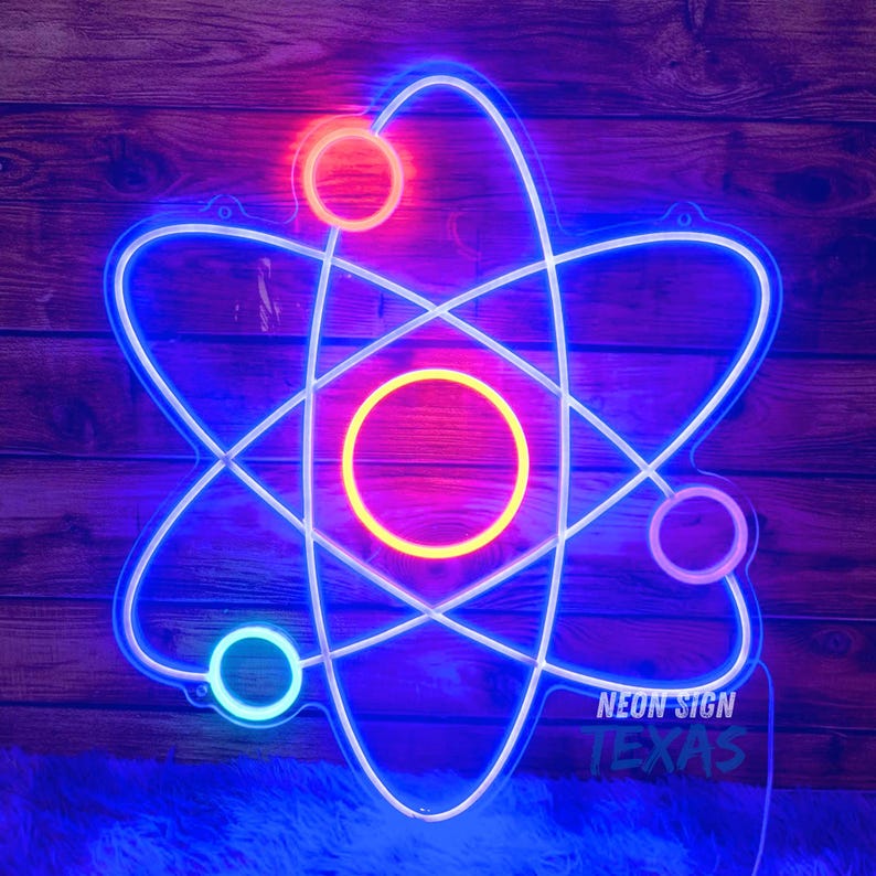 May include: A neon sign in the shape of an atom, with a blue outline and three circular accents in red, pink, and white. The sign has the text "NEON SIGN TEXAS" at the bottom. The sign is mounted on a wooden background.