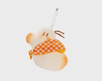 Könnte beinhalten: Ein plüschiges, cremefarbenes, entenförmiges Ornament mit orangefarbenen Akzenten an Schnabel und Unterseite. Es trägt einen orange-weiß karierten Schal und hat braunes Fadenhaar. Eine silberne Kette ist zum Aufhängen befestigt.