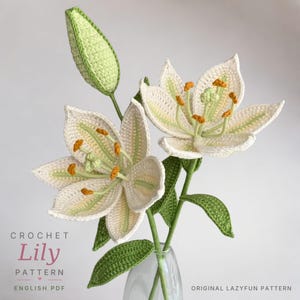 May include: Two crocheted white lilies with light green centers and orange stamens, plus one closed green bud. The stems have green leaves. Text on the image reads: CROCHET Lily PATTERN ENGLISH PDF and ORIGINAL LAZYFUN PATTERN.