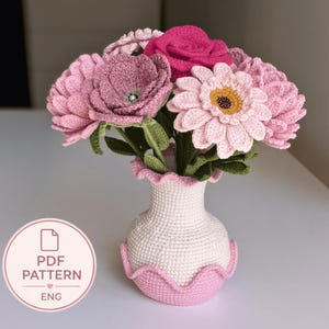 May include: A crochet bouquet featuring pink, magenta, and light pink flowers with green leaves arranged in a white and light pink crocheted vase. A circular badge in the corner displays the text PDF PATTERN ENG with a small heart icon.