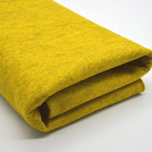 May include: A folded piece of yellow felt fabric. The fabric is soft and has a slightly textured surface.