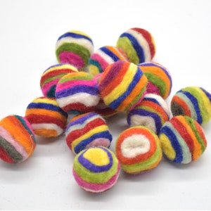 May include: A group of colourful felt balls with stripes of red, orange, yellow, green, blue, purple and white. The balls are arranged in a pile.