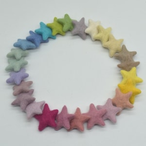 May include: A rainbow assortment of felt star shapes, arranged in a circle on a white background.