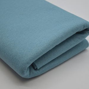 May include: A folded piece of light blue felt fabric. The fabric is soft and smooth, and it has a slightly fuzzy texture.