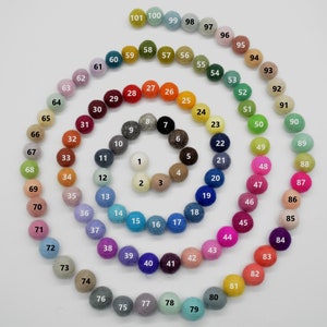 Puede incluir: Una carta de colores de 101 bolas de fieltro dispuestas en espiral. Las bolas están numeradas del 1 al 101, y cada bola es de un color diferente.