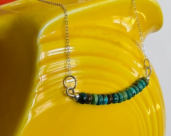 May include: A silver chain necklace with a row of turquoise and brown beads.