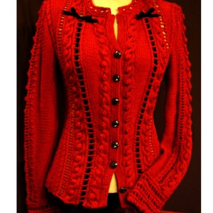 Peut inclure: Un cardigan rouge en tricot avec un motif en câble et des accents de ruban noir. Le cardigan a une fermeture boutonnée et des manches longues.
