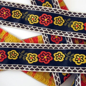 BAVARIAN DAISIES Jacquard trim. Orange, yellow, olive, ivory, brown on black. Sold by the yard. 2 inch wide. 2017-A